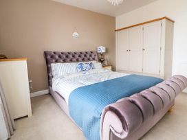A bedroom with a bed with blue and white bedding a nightstand with a lamp a dresser and a wardrobe at Buzzards View in Dyserth