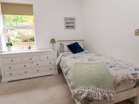 A bedroom with a single bed a white dresser and a window at Buzzards View in Dyserth