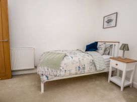 A bedroom with a single bed next to a nightstand with a lamp and a framed picture on the wall at Buzzards View in Dyserth