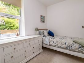 A bedroom with a single bed and a white dresser next to a window at Buzzards View in Dyserth