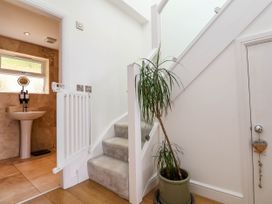 A hallway with a small staircase next to a potted plant and a bathroom with a pedestal sink in the background at Buzzards View in Dyserth