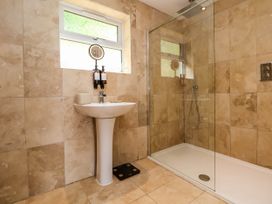 A bathroom with a pedestal sink and a walk-in shower with glass partition at Buzzards View in Dyserth