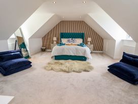 A bedroom with a teal bed and two blue chairs at Buzzards View in Dyserth