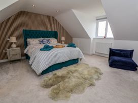 A bedroom with a bed with striped bedding two nightstands with lamps a sheepskin rug and a window at Buzzards View in Dyserth