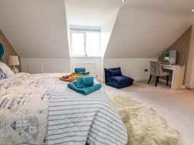 A bedroom with a bed partially visible with folded towels and a tray on it a window a folded blue chair a desk with a mirror and a chair at Buzzards View in Dyserth