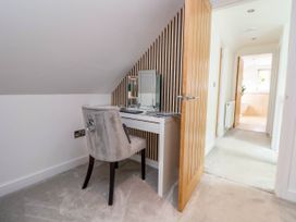 A small vanity desk with mirror and chair under a sloped ceiling in a hallway at Buzzards View in Dyserth