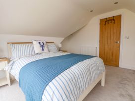 A bedroom with a bed with blue and white striped bedding and a wooden door at Buzzards View in Dyserth