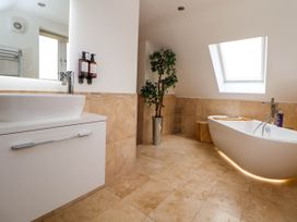 A bathroom with a white sink and cabinet a freestanding bathtub a skylight window and a potted plant at Buzzards View in Dyserth