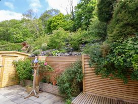 A garden with wooden fencing a shed a bird feeder and plants at Buzzards View in Dyserth