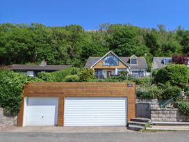 A house with a wooden garage door and bushes around at Buzzards View in Dyserth