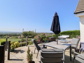 An outdoor patio with chairs table and umbrella overlooking fields and trees at Buzzards View in Dyserth