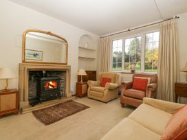 A living room with a fireplace a mirror two armchairs a sofa lamps and a large window overlooking a garden at The Coach House in Abergavenny