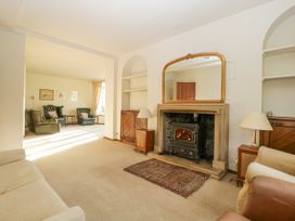 A living room with a fireplace a mirror above it and seating area in the background at The Coach House in Abergavenny