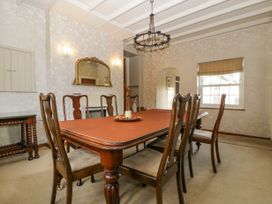 A dining room with a wooden table and six chairs a window with a blind and a mirror on the wall at The Coach House in Abergavenny