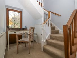 A small study area with a wooden desk and chair next to carpeted stairs with white railings at The Coach House in Abergavenny