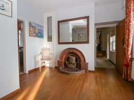 A room with a wooden floor a brick fireplace with logs a wooden chair a large mirror and wall art at The Coach House in Abergavenny