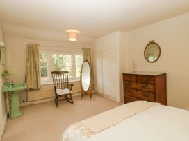 A bedroom with a green sink wooden rocking chair full length mirror chest of drawers and built in cupboard at The Coach House in Abergavenny