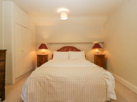 A bedroom with a double bed two bedside tables with lamps and built-in wardrobes at The Coach House in Abergavenny
