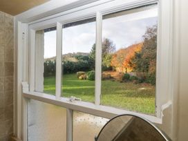 A window view of a grassy garden with bushes and trees in autumn at The Coach House in Abergavenny