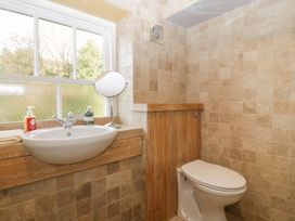 A bathroom with a white sink and toilet with tiled walls and a window at The Coach House in Abergavenny
