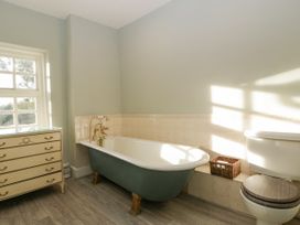 A bathroom with a bathtub toilet wicker basket and a chest of drawers at The Coach House in Abergavenny