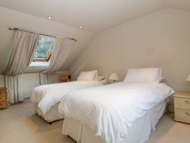 A bedroom with two single beds with white bedding a window with curtains and wooden furniture at The Coach House in Abergavenny