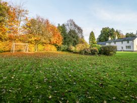 A grassy garden with fallen leaves bushes a soccer goal and a white house at The Coach House in Abergavenny