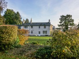 A white two story house with chimneys surrounded by a garden with bushes and trees at The Coach House in Abergavenny