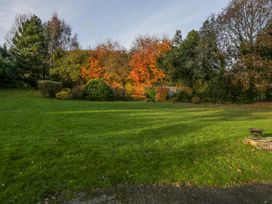 A grassy garden area with bushes and trees with autumn foliage at The Coach House in Abergavenny