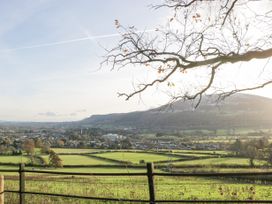 A rural landscape with fields trees and houses with hills in the background at The Coach House in Abergavenny