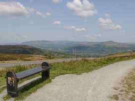 A bench next to a gravel path with hills and a road in the background at The Coach House in Abergavenny
