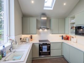 A kitchen with green cabinets and modern appliances at The Old Cottage in Oxen Park near Ulverston
