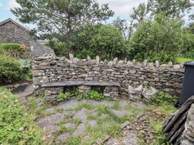 A garden area with a stone wall and wooden bench at Old Cottage in Oxen Park near Ulverston