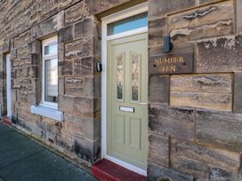 Stone exterior wall with a green door and a window next to it and a plaque reading Number Ten at Number Ten in Amble