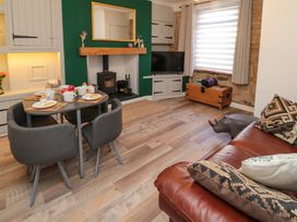 A living room with a dining table set for breakfast a wood stove a television and a leather sofa at Number Ten in Amble