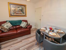 A dining area with a table set for four and a leather sofa with cushions and a framed artwork on the wall at Number Ten in Amble