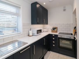 A kitchen with black cabinets a white countertop a microwave toaster oven and window blinds at Number Ten in Amble
