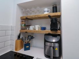 Wooden shelves with glasses cups and a coffee machine above an air fryer in a kitchen alcove at Number Ten in Amble