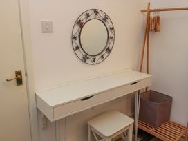 A dressing table with drawers a stool a round wall mirror with butterfly designs and a wooden clothing rack with hangers and a storage basket at Number Ten in Amble