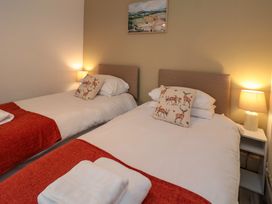A bedroom with two single beds with deer print cushions and lamps on bedside tables at Number Ten in Amble