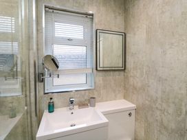 A bathroom with a sink a mirror a window with blinds and a soap dispenser at Number Ten in Amble