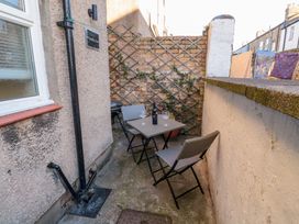 A small outdoor patio area with a table and two chairs and a bottle of wine at Number Ten in Amble