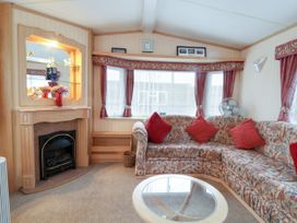 A living room with a corner sofa with red cushions a fireplace and a glass coffee table at Willebby in South Chard