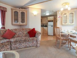 A living area with a patterned sofa and red cushions next to a dining table and chairs with a kitchen in the background at Willebby in South Chard