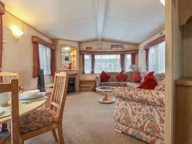 A living room with a dining table wooden chairs floral sofa and cushions at Willebby in South Chard