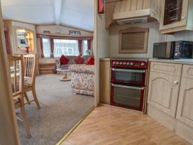 A kitchen area with a red oven and microwave next to a living room with floral sofas and wooden chairs at Willebby in South Chard