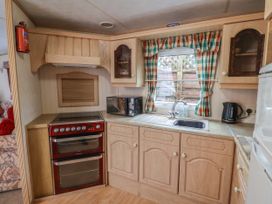 A kitchen with a red double oven a microwave a sink with plaid curtains on the window and wooden cabinets at Willebby in South Chard