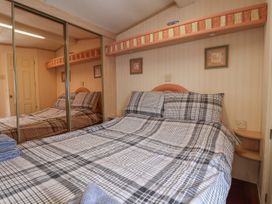 A bedroom with a double bed with checkered bedding, mirrored wardrobes, and small framed pictures above the bed at Willebby in South Chard