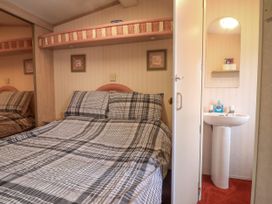 A bedroom with a bed and plaid bedding next to a sink and mirror at Willebby South Chard
