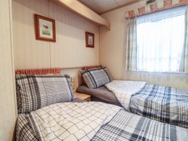 A bedroom with two single beds with checkered bedding a window with curtains and two framed pictures on the wall at Willebby in South Chard